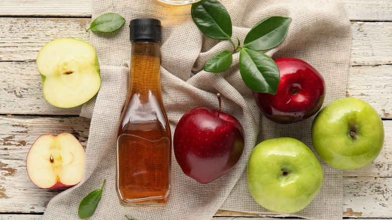 Top-down view of apples and a bottle of apple cider vinegar