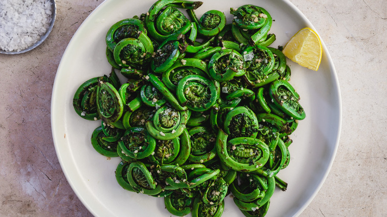 Sautéed ferns in plate with lemon.