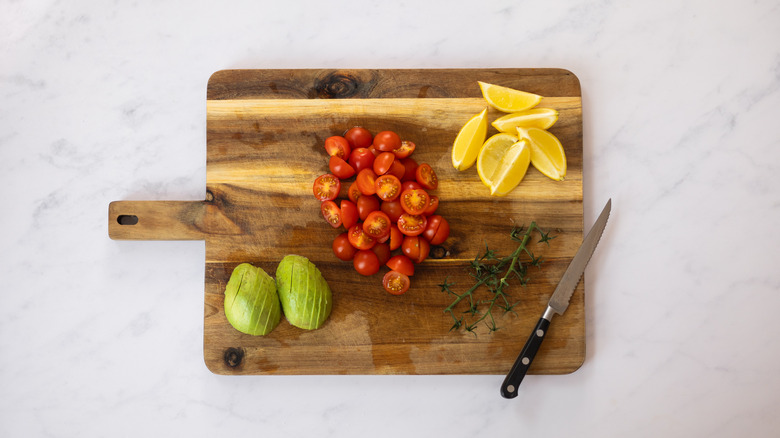 avocado, tomatoes and lemon on chopping board 