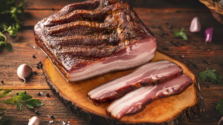 Sliced dry-cured pork belly on a wooden slab