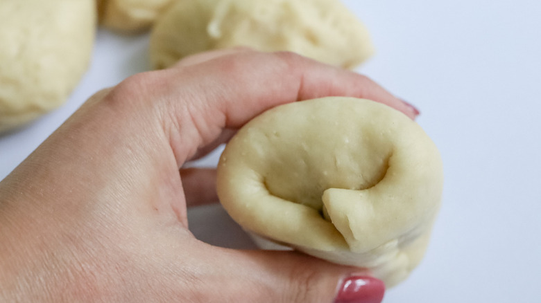 hand holding unbaked kolach