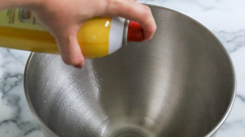 hand spraying cooking spray into bowl