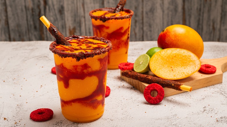 Two mangonadas with sliced mango and lime