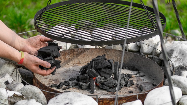 placing charcoal under tripod grill