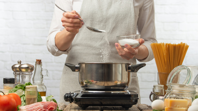 chef adding salt to hot water