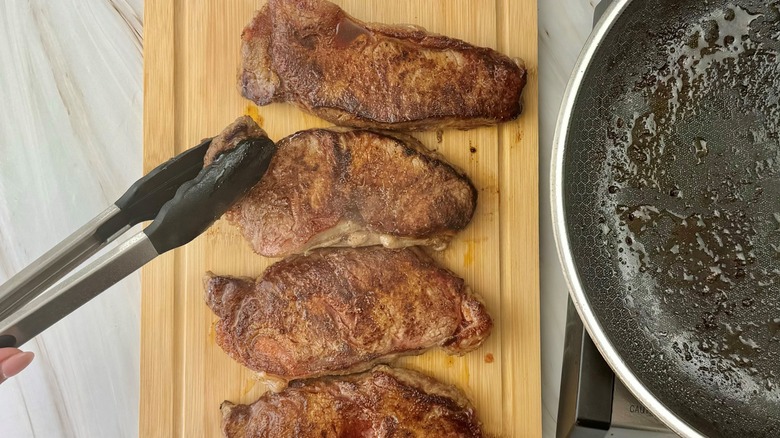 finger with tongs and steaks