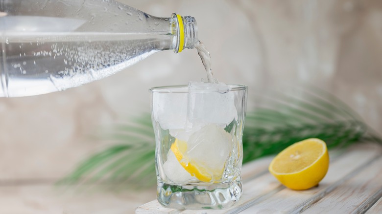 Pouring club soda over ice and lemon
