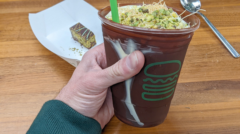 Squeezing Shake Shack's Dubai Chocolate Pistachio Shake to shatter the chocolate shell