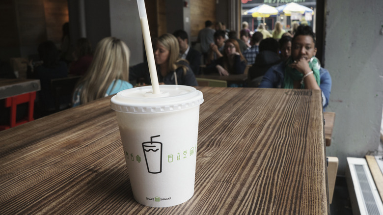 Shake Shack milkshake on a wood table with customers in the background