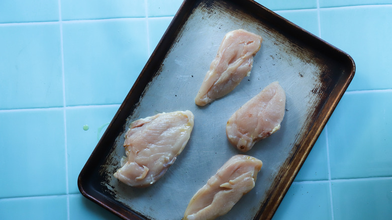 Raw chicken breasts on tray