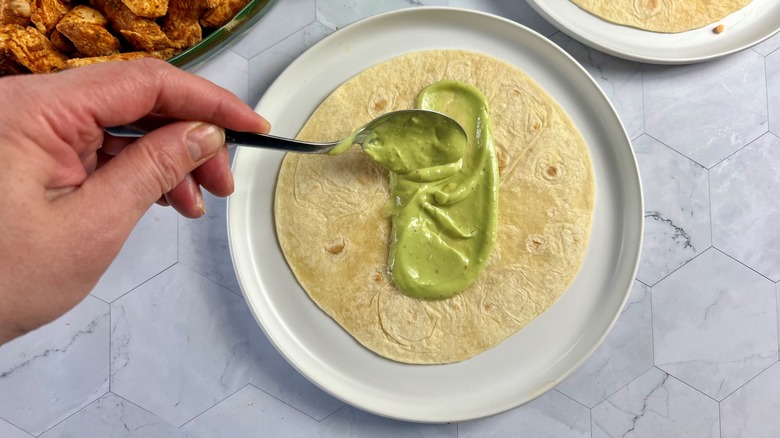 hand smearing sauce on tortilla