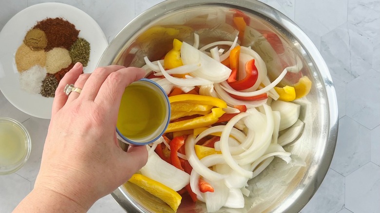 hand pouring oil on vegetables