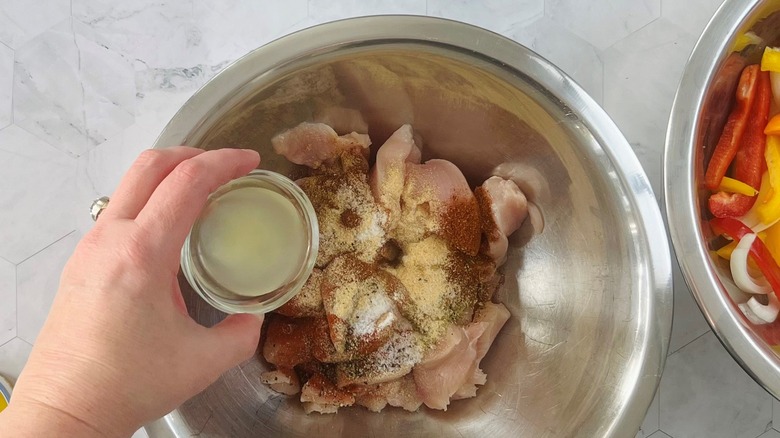 hand pouring juice on chicken