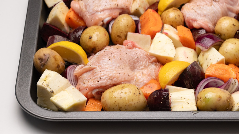 uncooked chicken and vegetables on sheet pan