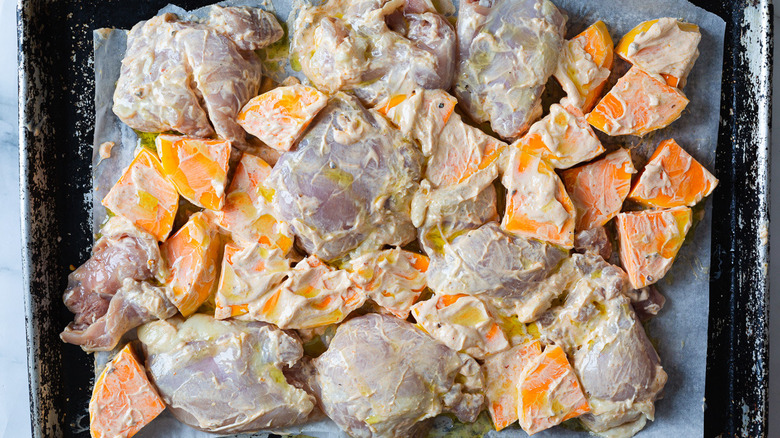 Chicken and squash in sauce on baking sheet