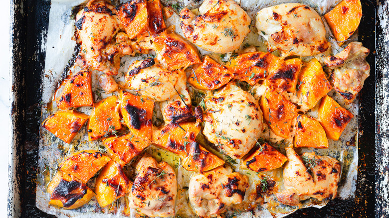 Baked chicken and squash on baking sheet