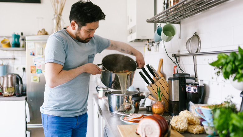 Asian man pouring ramen broth