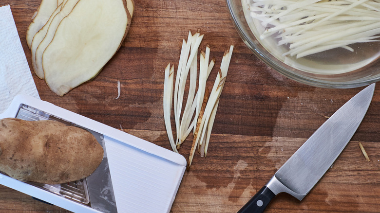 slicing slices of potato on cutting board