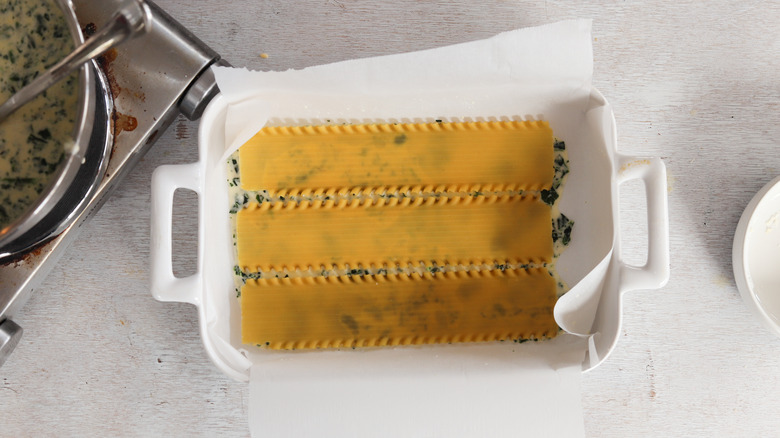 spinach sauce and lasagna noodles in baking dish