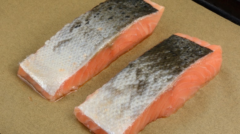 Two raw salmon filets, skin side up, on paper