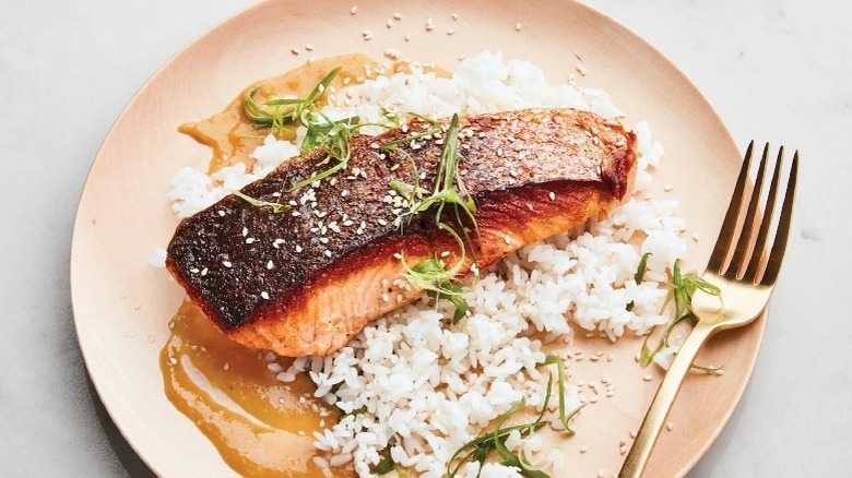 A cooked salmon filet over rice, crispy skin side up