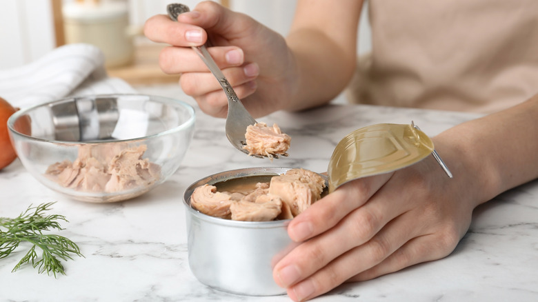 person putting tuna in a bowl