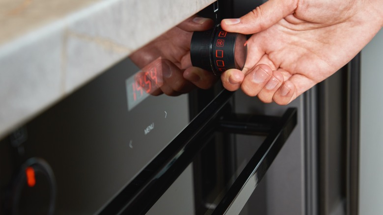 man's hand turning on oven