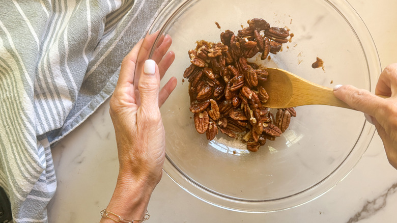 hand stirring pecan in bowl