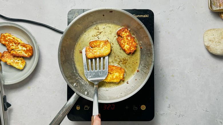 frying halloumi in skillet, flipping with spatula