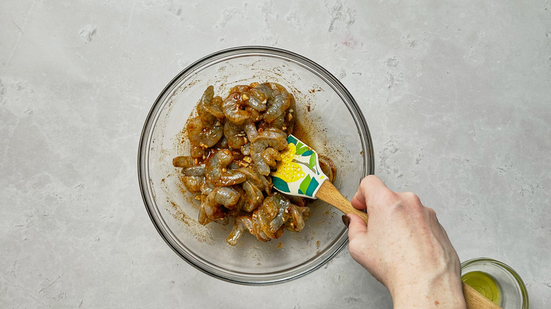 stirring shrimp with seasonings with rubber spatula