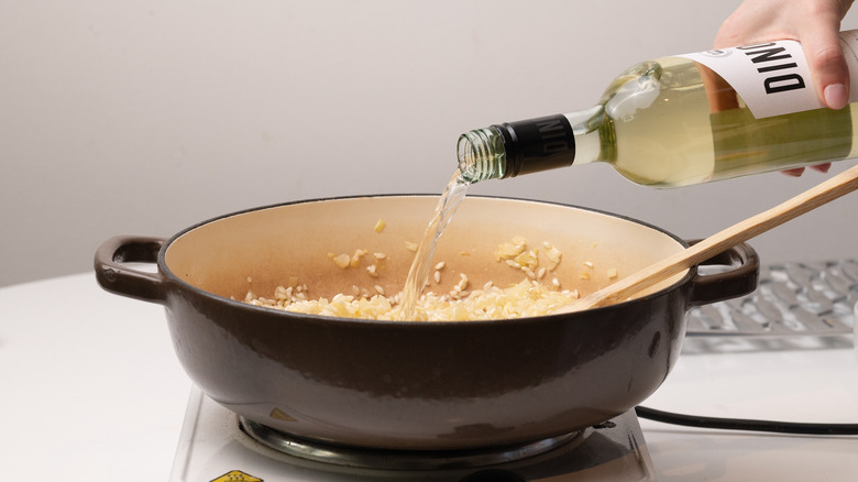 pouring white wine into risotto