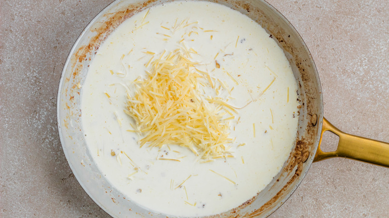 adding parmesan to alfredo sauce