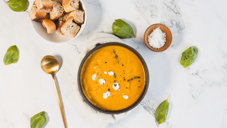 Overhead bowl of carrot soup with croutons and basil