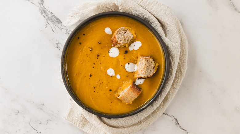 Overhead bowl of carrot soup with napkin