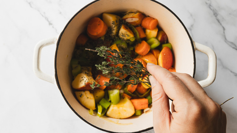 Adding thyme to pot of soup