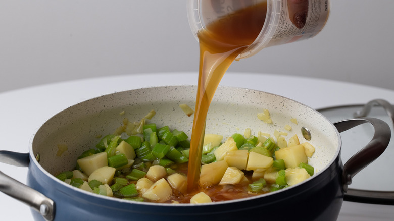 pouring stock into saucepan