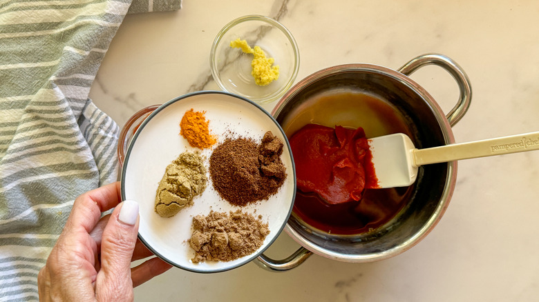 hand adding spices to pot