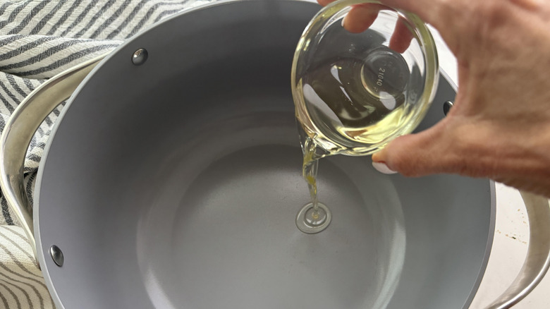 hand adding oil to pot