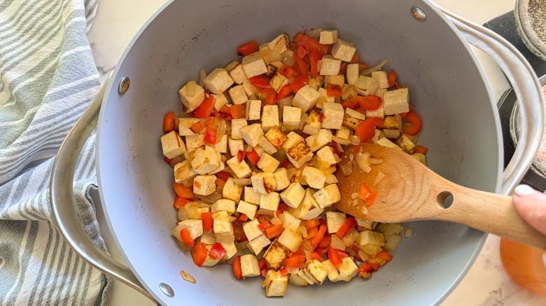 hand stirring tofu and vegetables