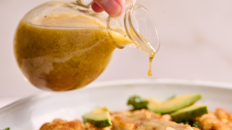 pouring salad dressing over salad