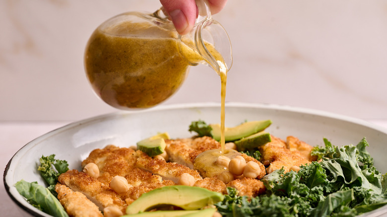 pouring salad dressing over salad