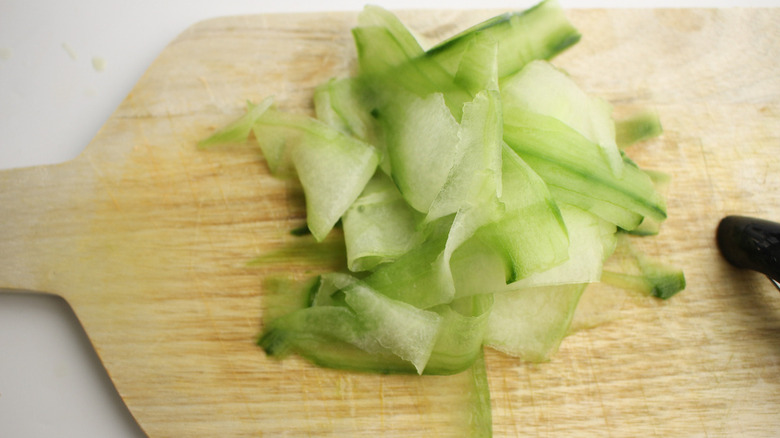 peeled, sliced cucumbers on board