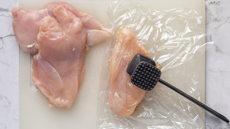 pounding plastic-wrapped chicken breasts 