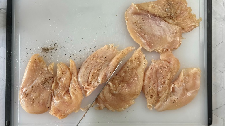 knife halving butterflied chicken on cutting board