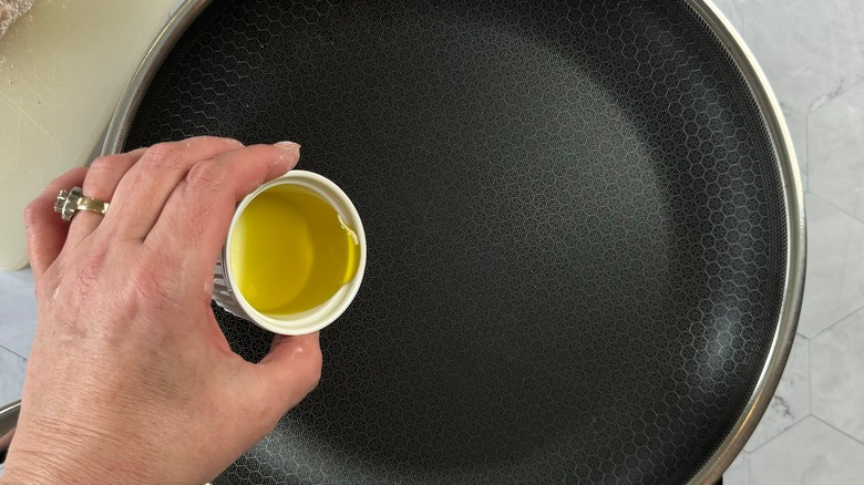 hand pouring oil into skillet