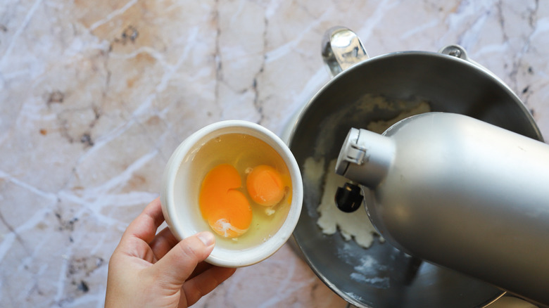 Eggs adding into mixer bowl