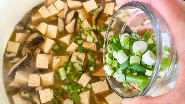 adding scallions to miso soup pot