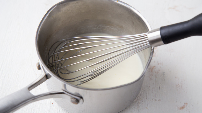 whisking white sauce in pan