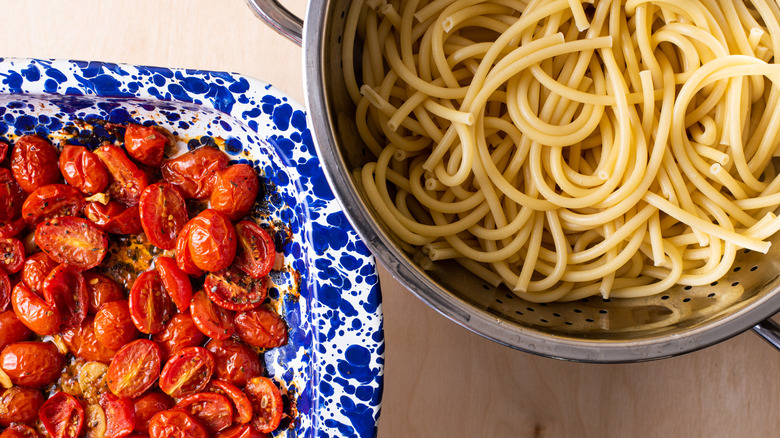 Roasted tomatoes and bucatini in a colander.