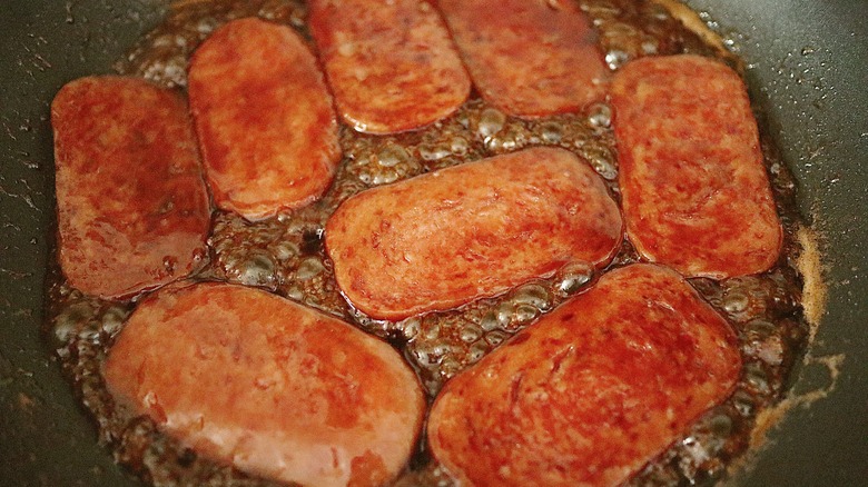 spam slices cooking in sauce